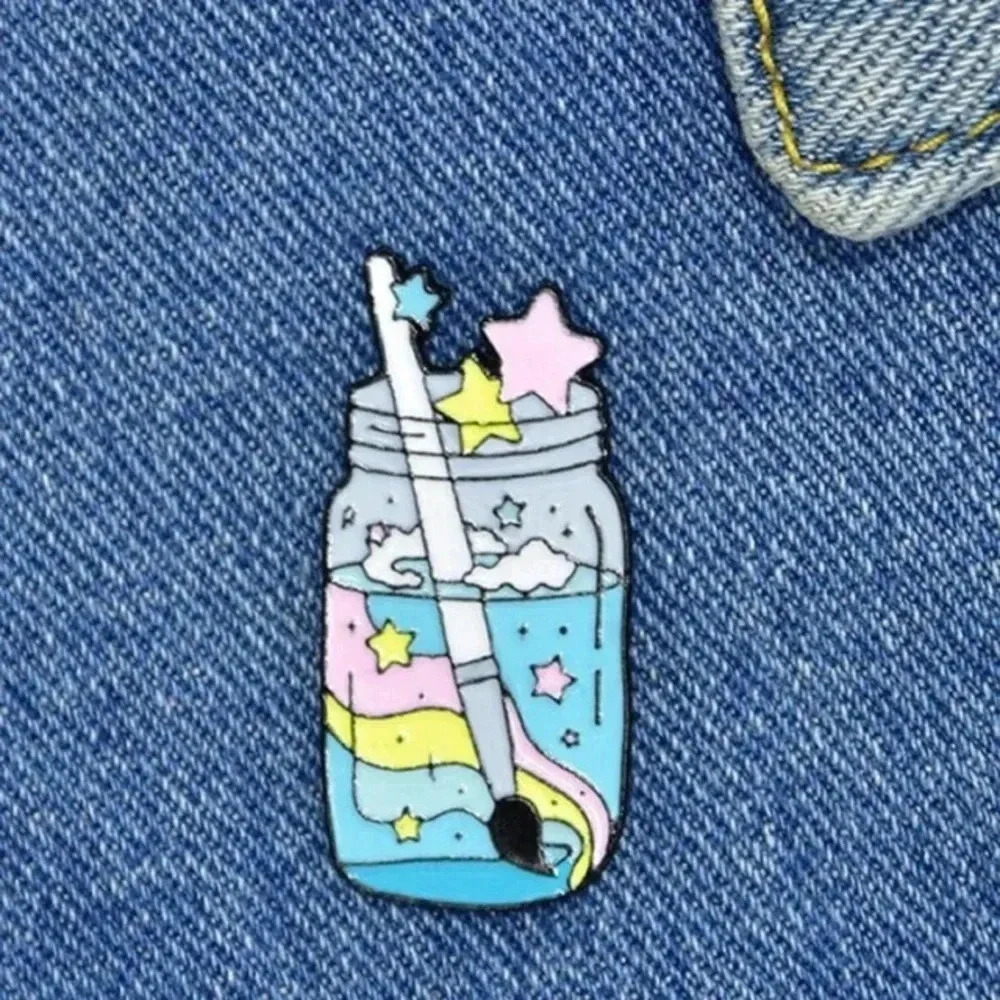 Blue yellow pink rainbow mason jar holding paintbrush stars artist enamel pin